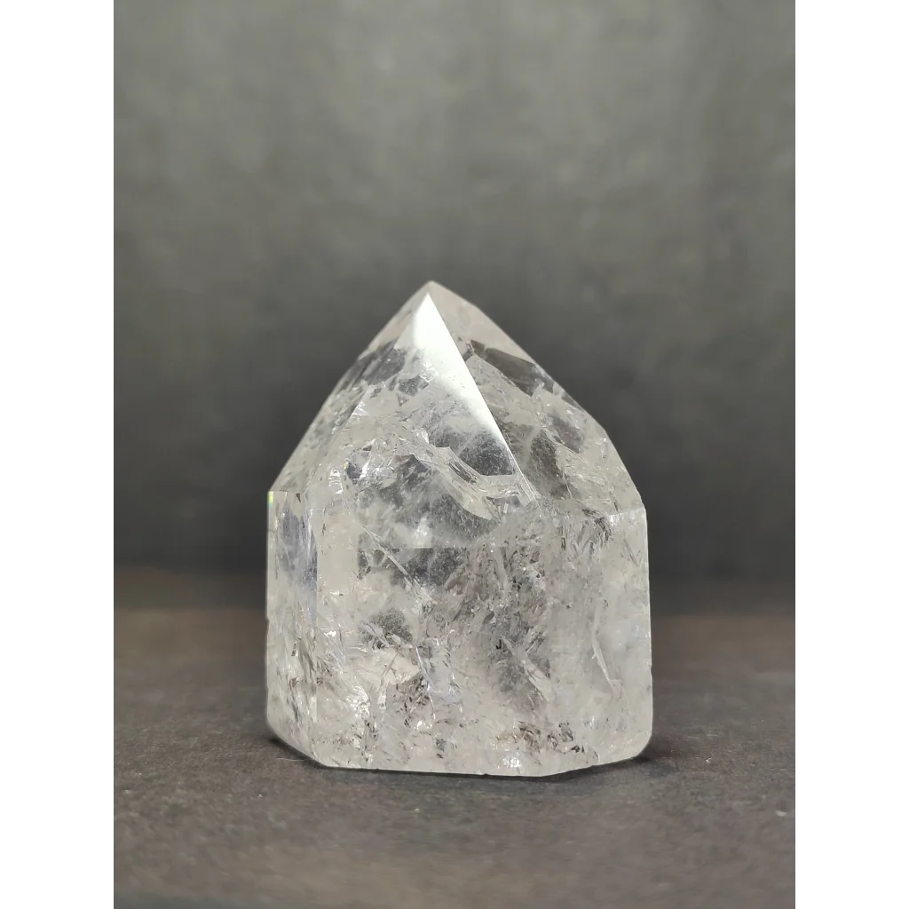 Clear crackle quartz point with a pointed top and faceted sides showing natural internal inclusions