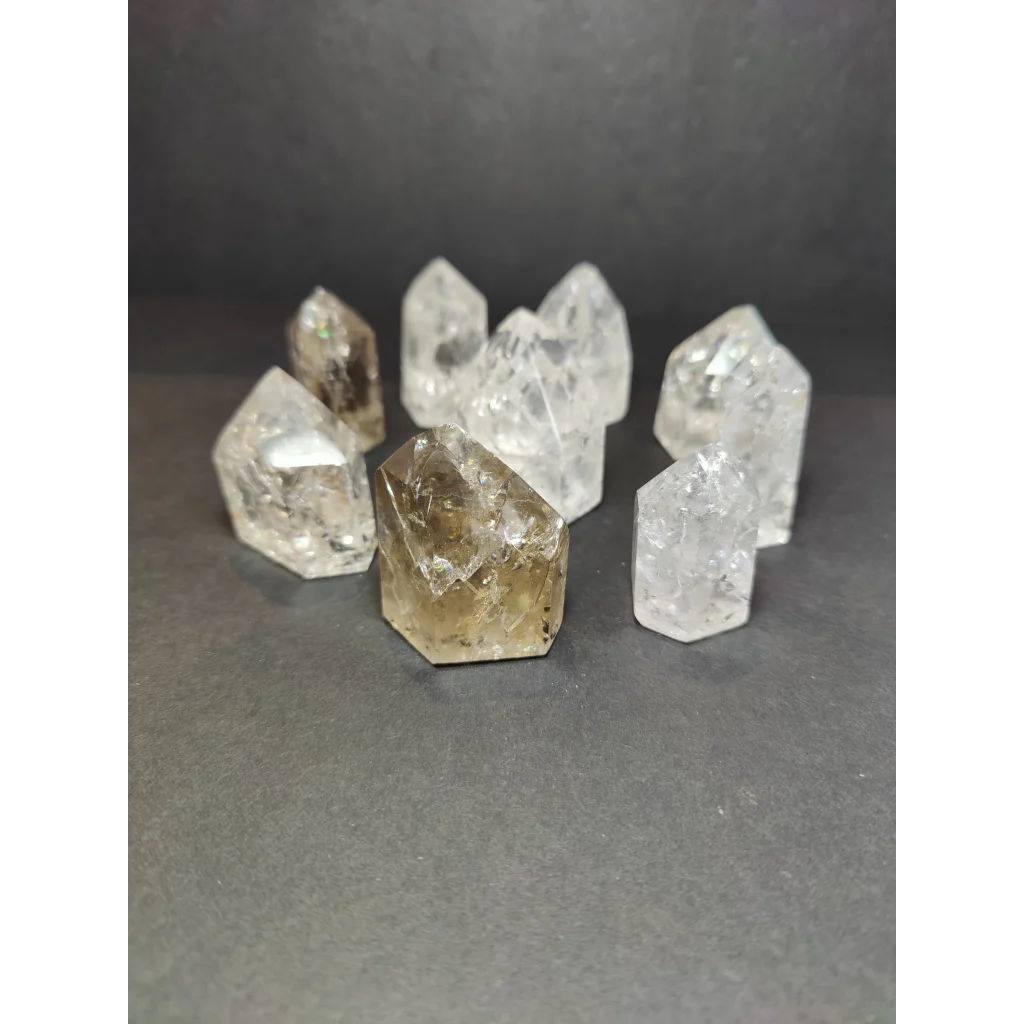 A collection of clear and smoky crackle quartz points with faceted geometric designs in crackle quartz point style