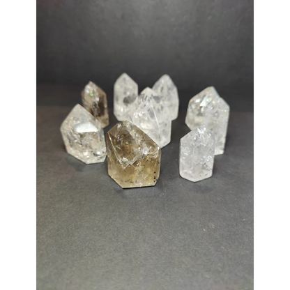 A collection of clear and smoky crackle quartz points with faceted geometric designs in crackle quartz point style