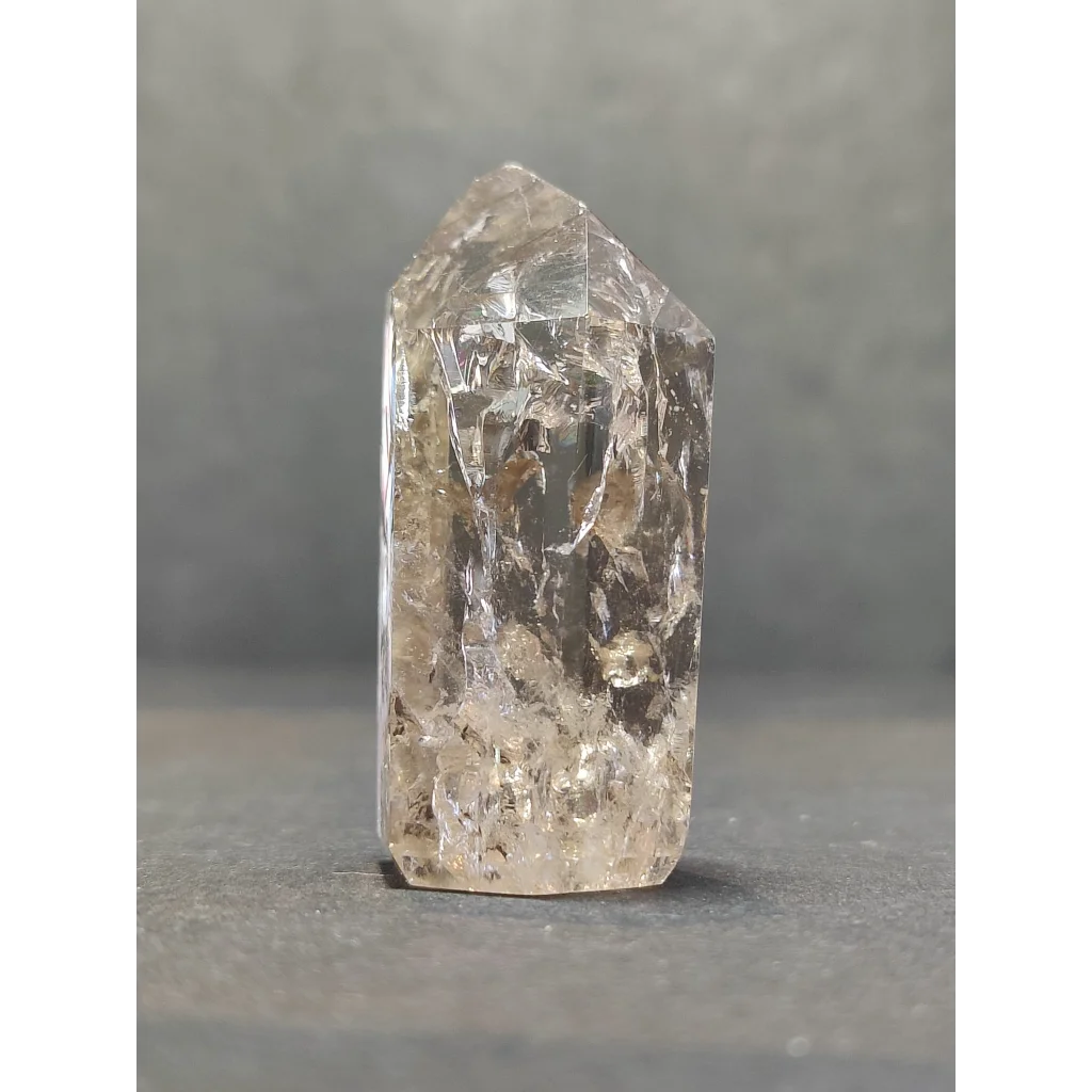 A clear crackle quartz point with natural inclusions and a faceted pointed top for crystal healing