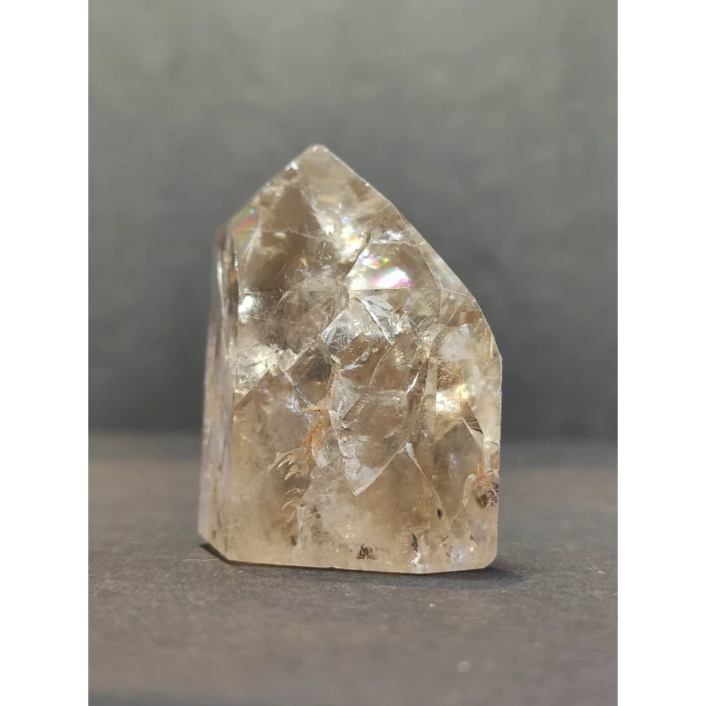 A translucent pale yellow crackle quartz point with faceted surfaces and a pointed top crystal