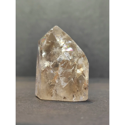 A translucent pale yellow crackle quartz point with faceted surfaces and a pointed top crystal