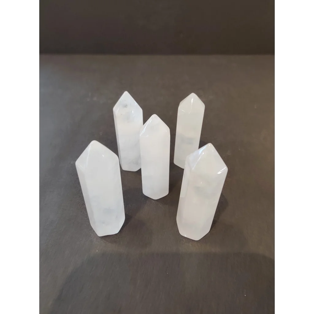 Five translucent white quartz crystal cut base tower sculptures on dark surface