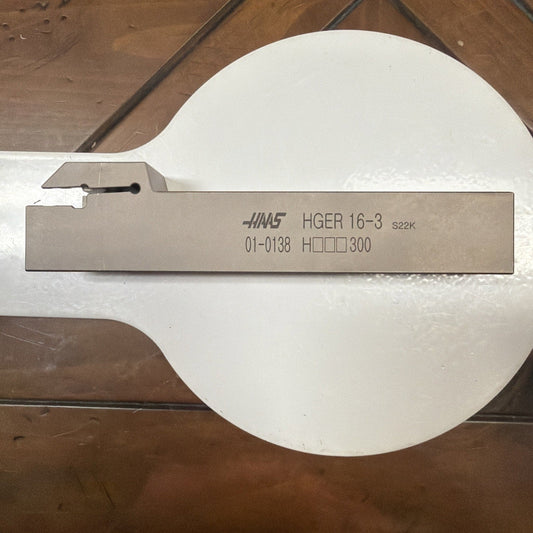 HAAS HGER 16-3 external grooving tool holder displayed on white paper against wooden floor, showing engraved part number and specifications.