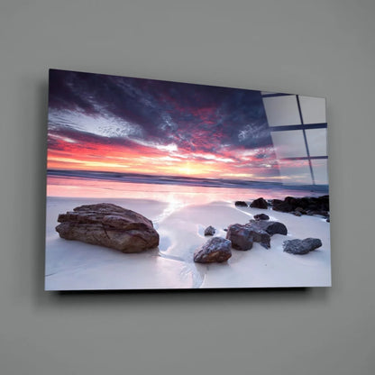 Beige-framed canvas wall art of vibrant pink purple sunset over beach rocks
