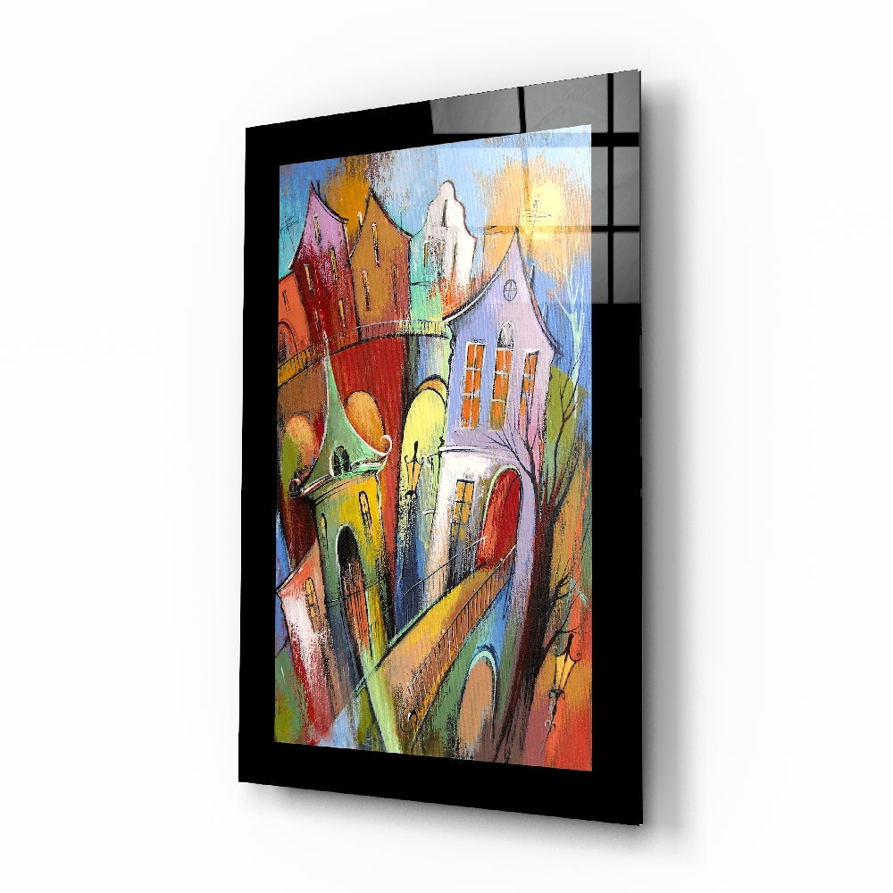 Colorful whimsical village street scene with multi-colored houses and church rendered on black-framed glass wall art.
