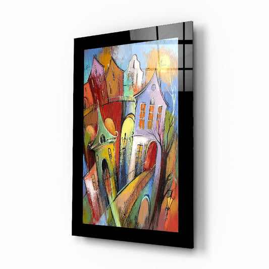 Colorful whimsical village street scene with multi-colored houses and church rendered on black-framed glass wall art.