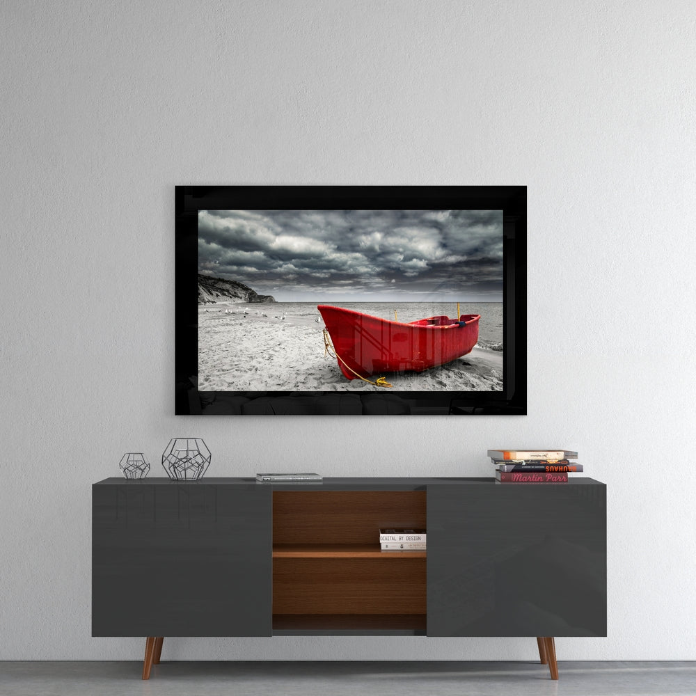 Red boat glass wall art mounted above a mid-century modern credenza, displaying a stormy beach scene with dramatic clouds.