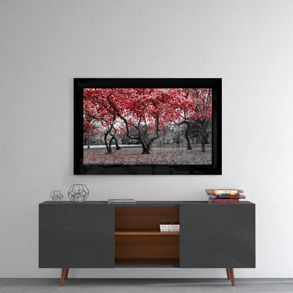 Black-framed glass wall art displaying red tree foliage in selective color above a dark and wood media console.