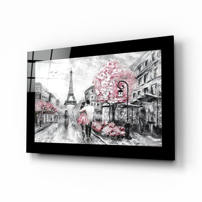 Black-framed glass wall art displaying a Paris street scene in grayscale with pink flowering trees and the Eiffel Tower, mounted at an angle.