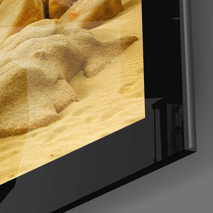 Close-up angled view of framed glass wall art displaying textured sand and rock formations in warm beige and tan tones.