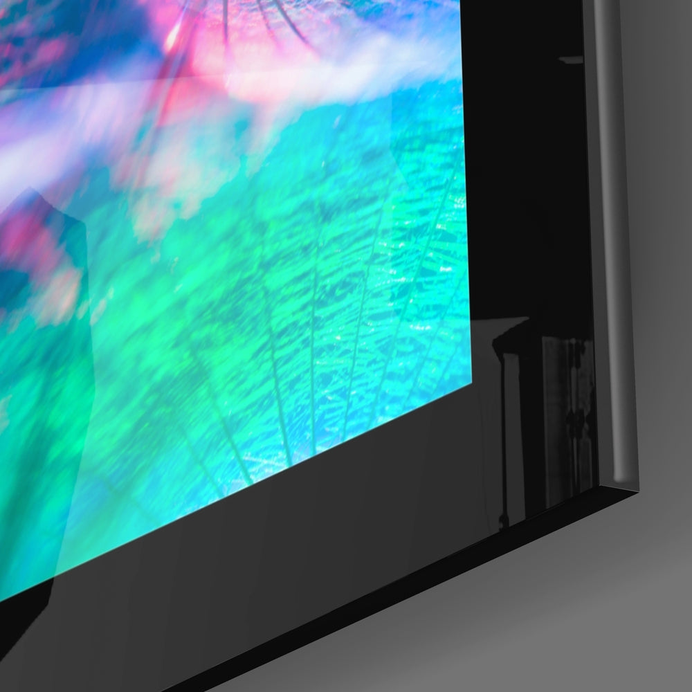 Angled view of glass wall art displaying vibrant turquoise, pink, and blue gradient with flowing patterns mounted on dark stand.