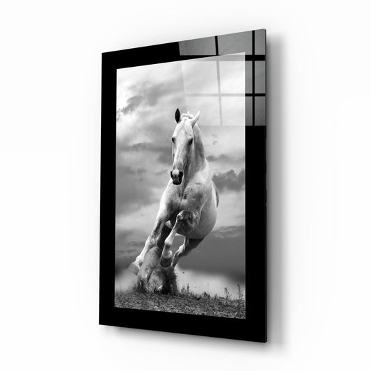 Black-framed glass wall art displaying a black and white photograph of a white horse galloping toward the camera against a cloudy sky.