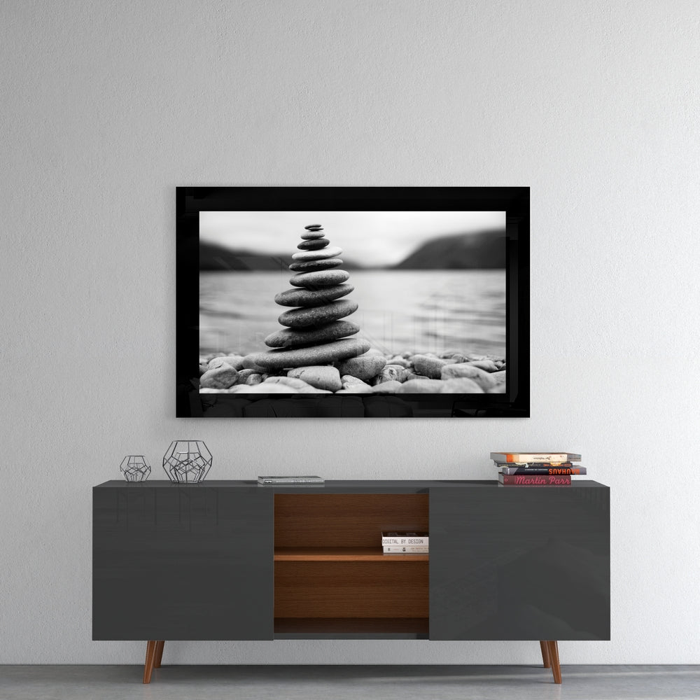 Black-framed glass wall art displaying stacked stones by a lake in black and white, mounted above a mid-century modern console table.