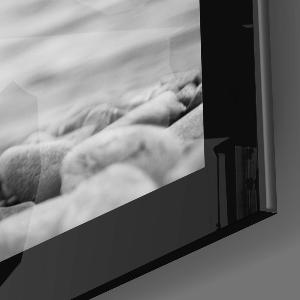 Close-up angled view of black-framed glass wall art displaying monochrome photograph of folded white bedding or linens.