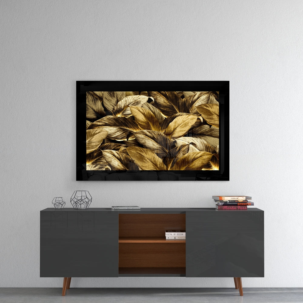 Black-framed glass wall art displaying golden and brown layered leaves hung above a mid-century modern console table.