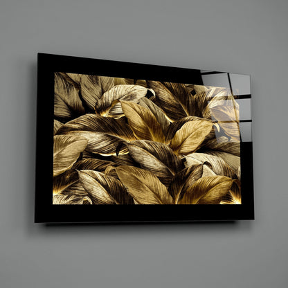 Black-framed glass wall art displaying close-up golden and brown leaves mounted on gray wall.