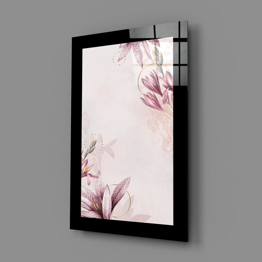 Black-framed glass wall art displaying delicate pink flowers and gold accents on cream background, angled perspective view.