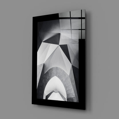 Black-framed glass wall art displaying upward architectural photography in grayscale, mounted at angle against gray background.