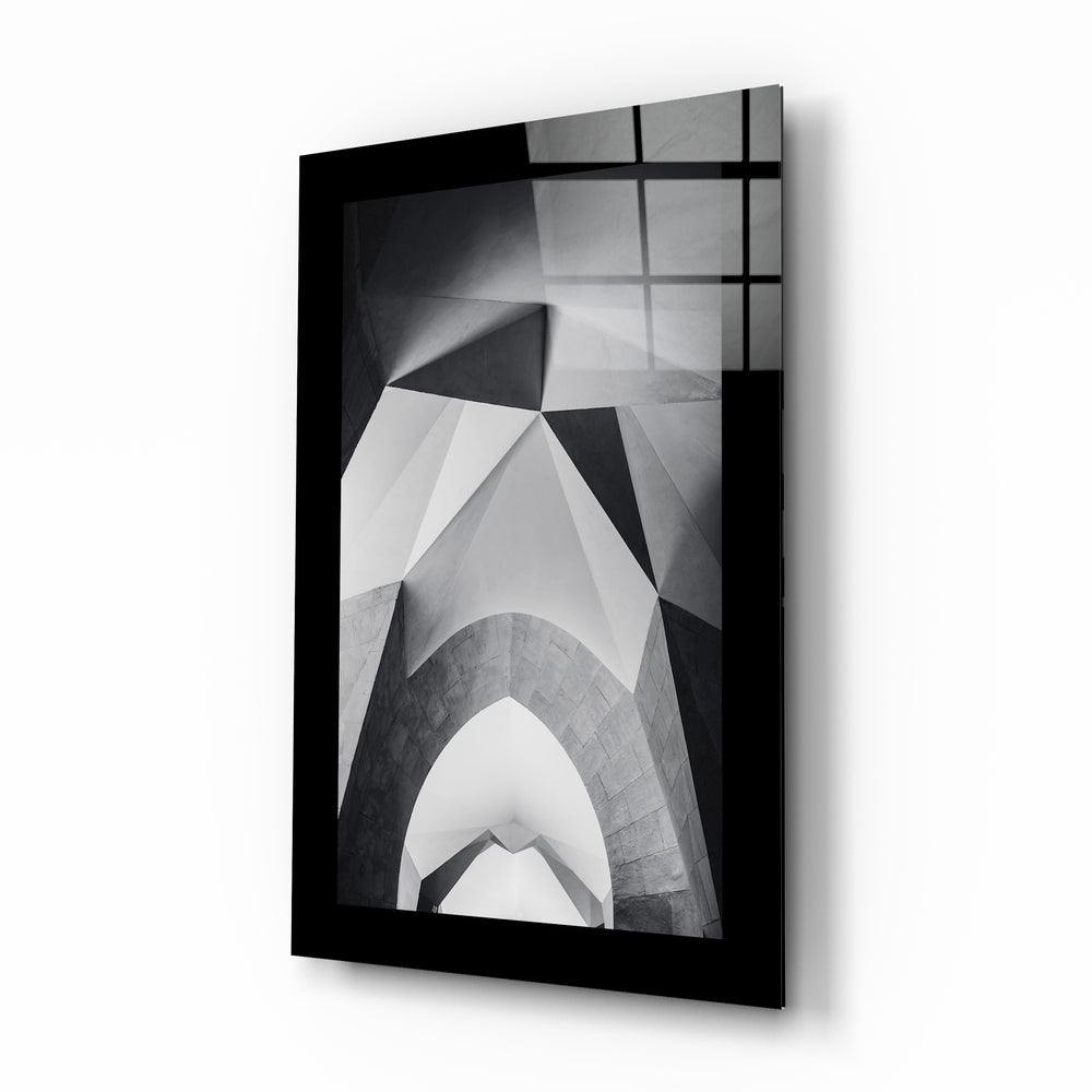 Black-framed glass wall art displaying black and white architectural photograph of upward-looking building arches and geometric patterns.