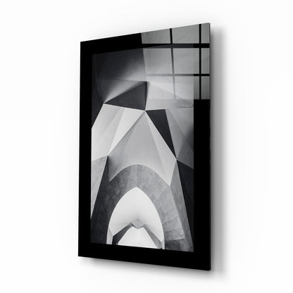 Black-framed glass wall art displaying black and white architectural photograph of upward-looking building arches and geometric patterns.