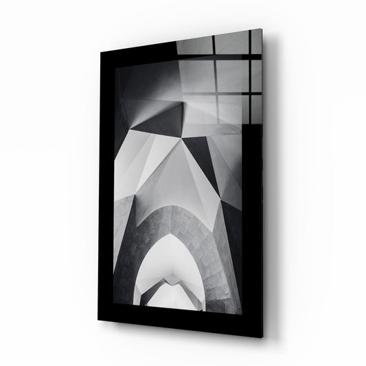 Black-framed glass wall art displaying black and white architectural photograph of upward-looking building arches and geometric patterns.