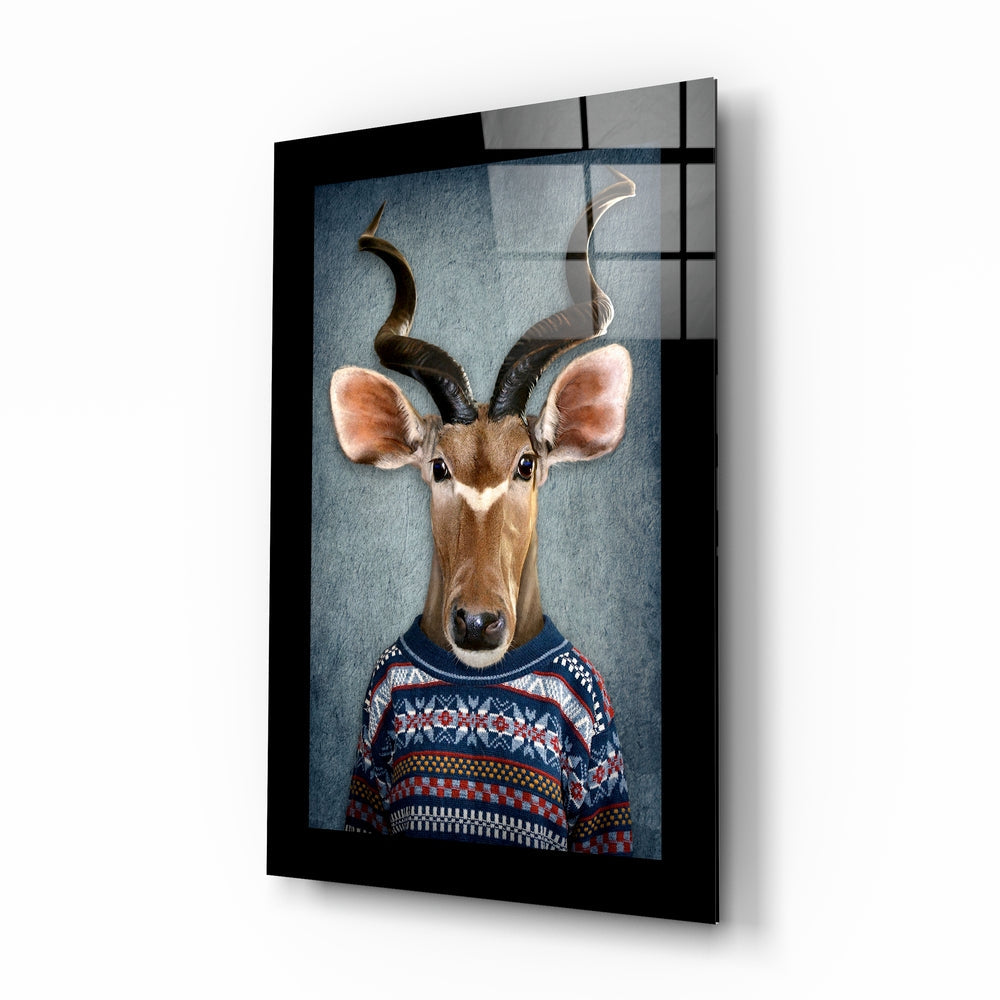 Framed glass wall art displaying an antelope with spiraled horns wearing a navy and red patterned sweater against a blue background.
