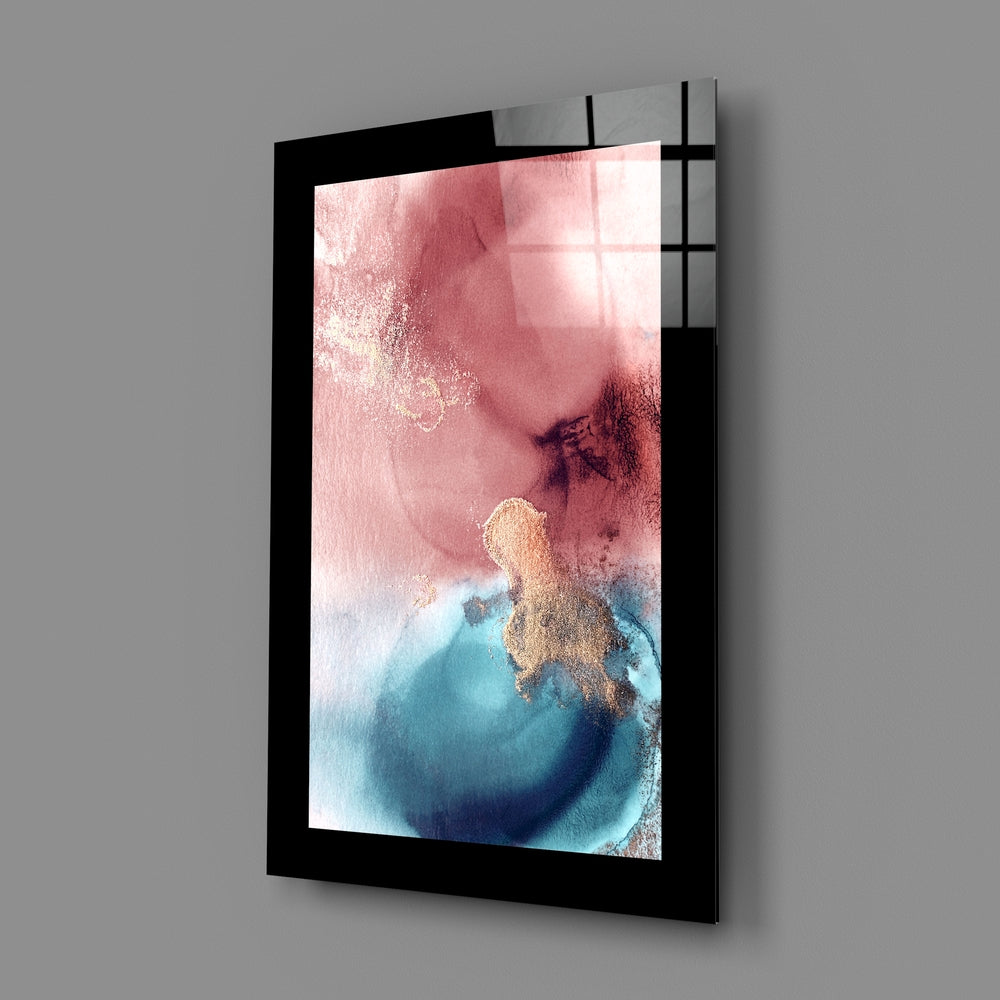 Black-framed glass wall art displaying abstract watercolor in pink, blue, and gold tones, mounted at angle against gray wall.