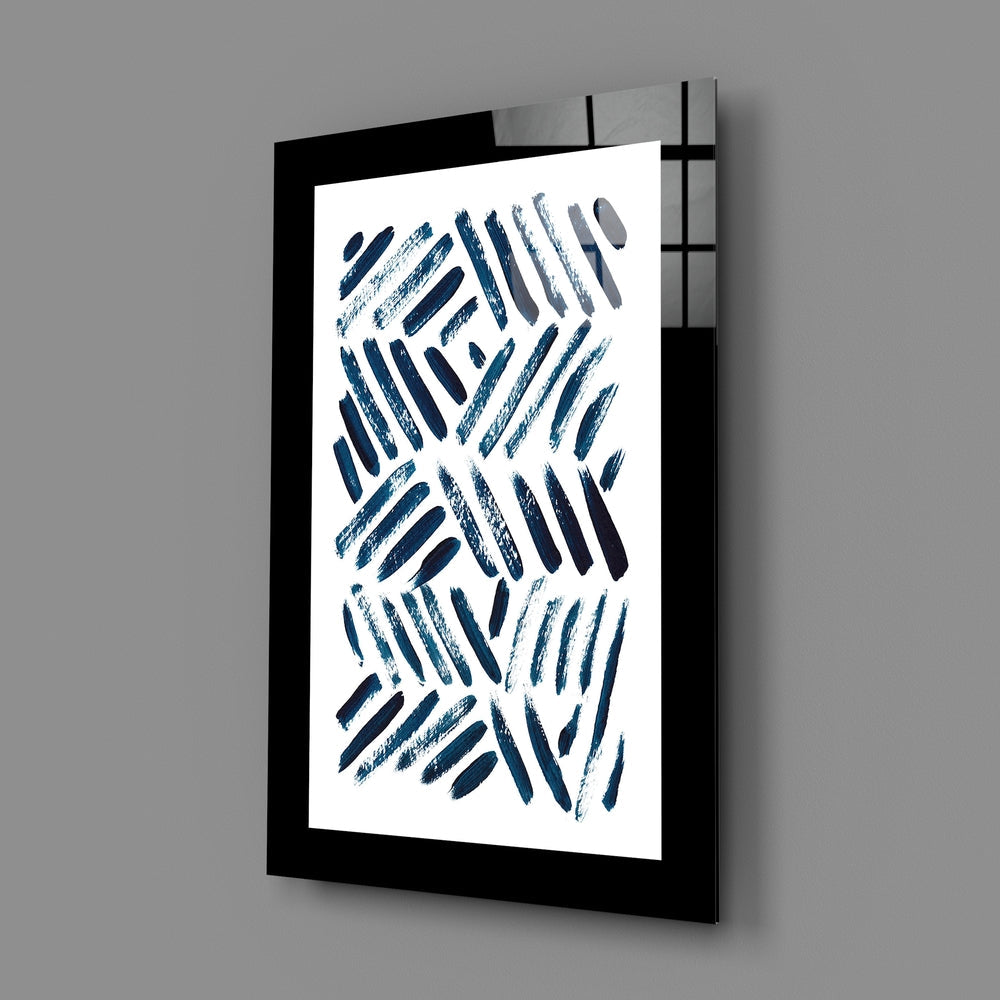 Black-framed glass wall art displaying diagonal blue brushstrokes on white background, angled view showing depth and shadow.