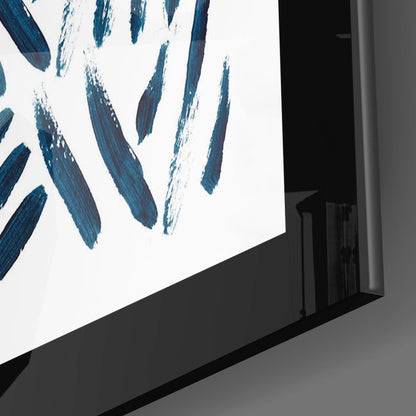 Angled view of glass wall art with blue and white brushstroke design mounted on gray wall.