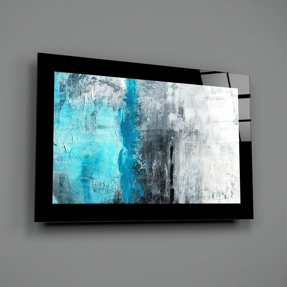 Black-framed glass wall art displaying abstract turquoise and white brushstroke design, mounted on gray wall.