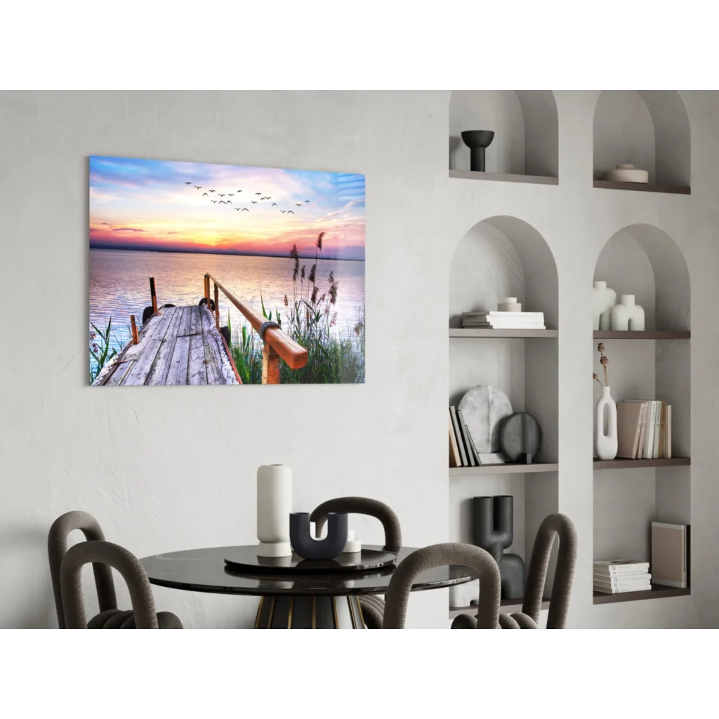 Serene sunset over water on glass wall art with dock, reeds, birds