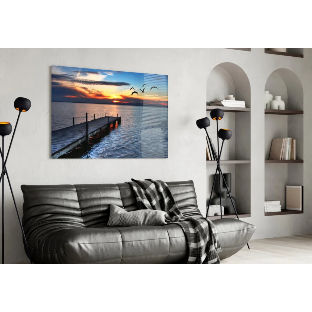 Sleek gray leather sofa with quilted texture and plaid throw under Sunset Pier glass wall art