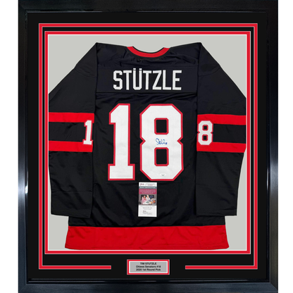 Black Ottawa Senators hockey jersey number 18 with "STUTZLE" nameplate, signed, displayed framed with red and white matting.