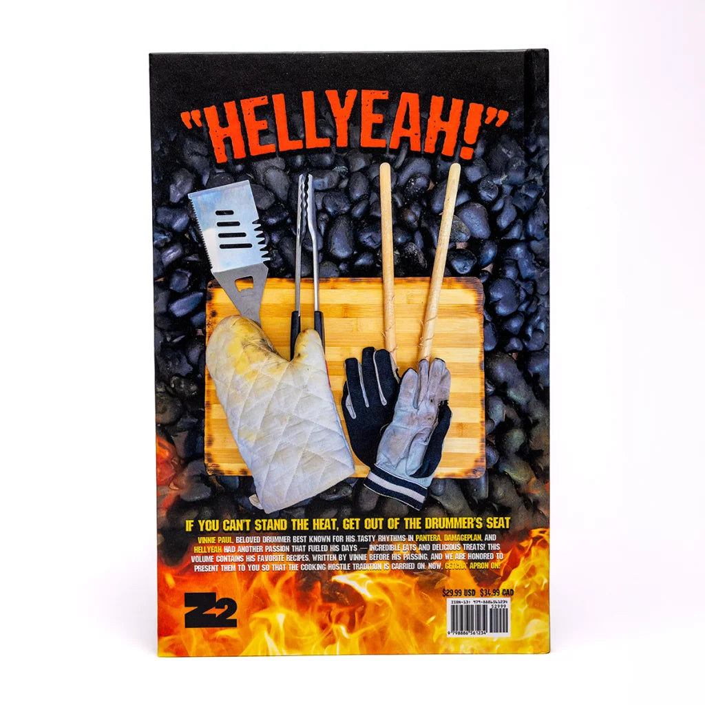 Vinnie Paul Abbott cookbook with grilling tools, oven mitts, drumsticks on charcoal