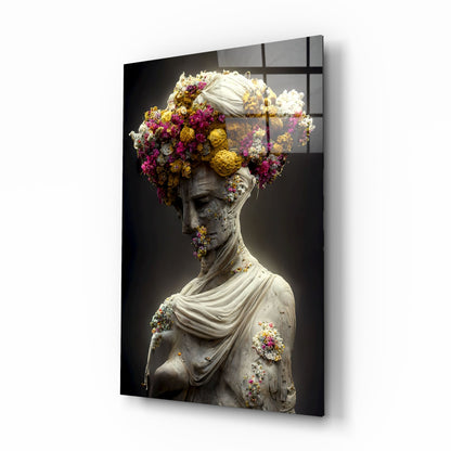Classical stone bust adorned with vibrant purple, yellow, and white flowers against dark background on glass panel.