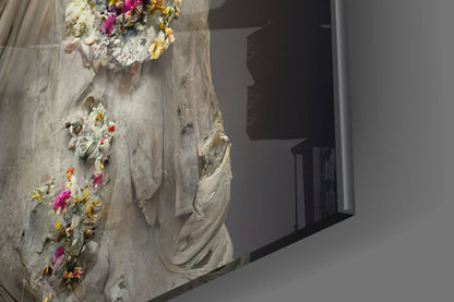 Close-up of textured stone wall art with colorful flowers (pink, yellow, orange) embedded in white plaster, beside a dark doorway opening.