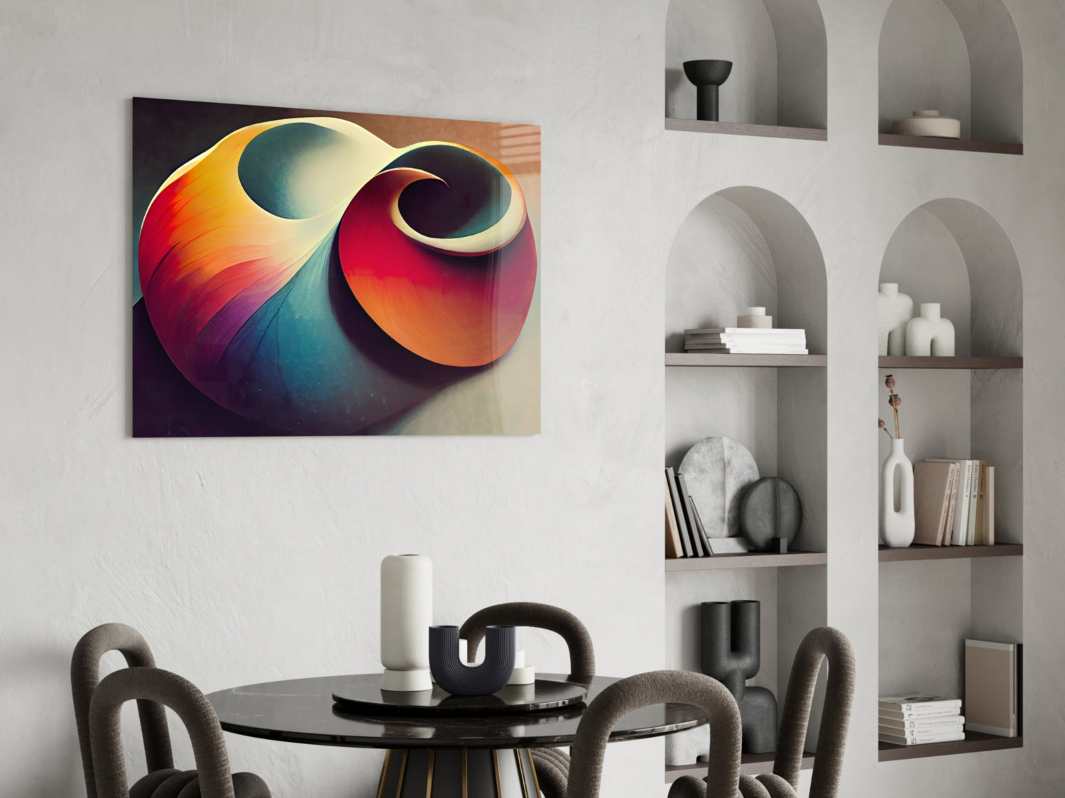 Colorful abstract shell art canvas with red, orange, yellow, and teal gradients hanging above a round black table in a modern interior space.