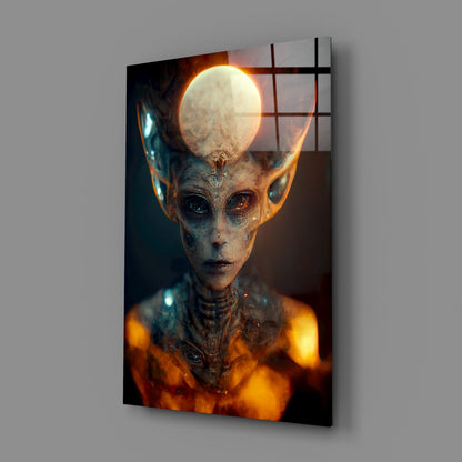 Glass art panel displaying an otherworldly alien figure with elongated head, glowing orb, textured skin, and orange luminescent aura against dark background.