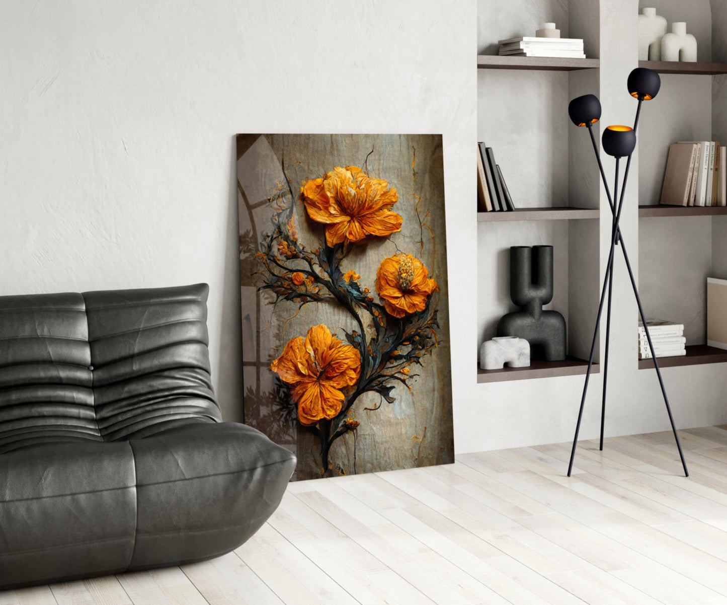 Modern living room with glass art featuring three orange flowers on dark branches, displayed against white wall beside gray leather chair and black floor lamp.