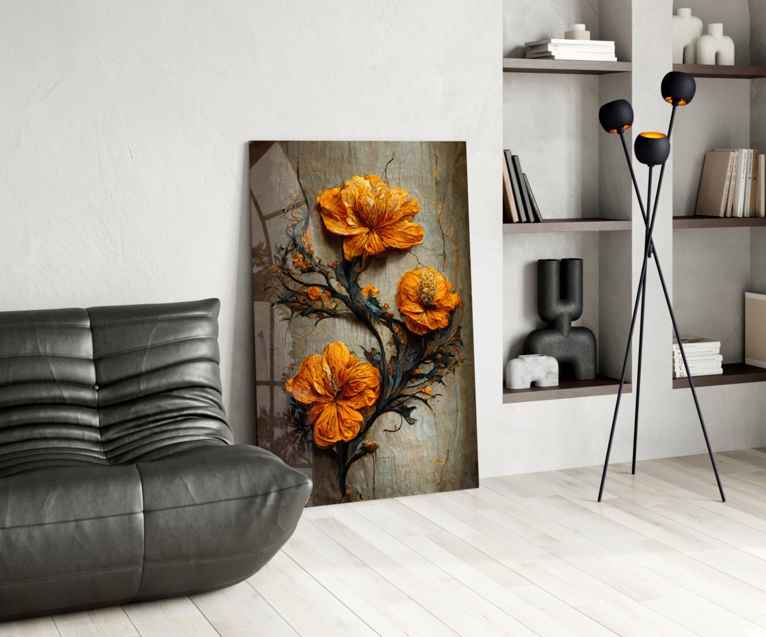 Modern living room with glass art featuring three orange flowers on dark branches, displayed against white wall beside gray leather chair and black floor lamp.