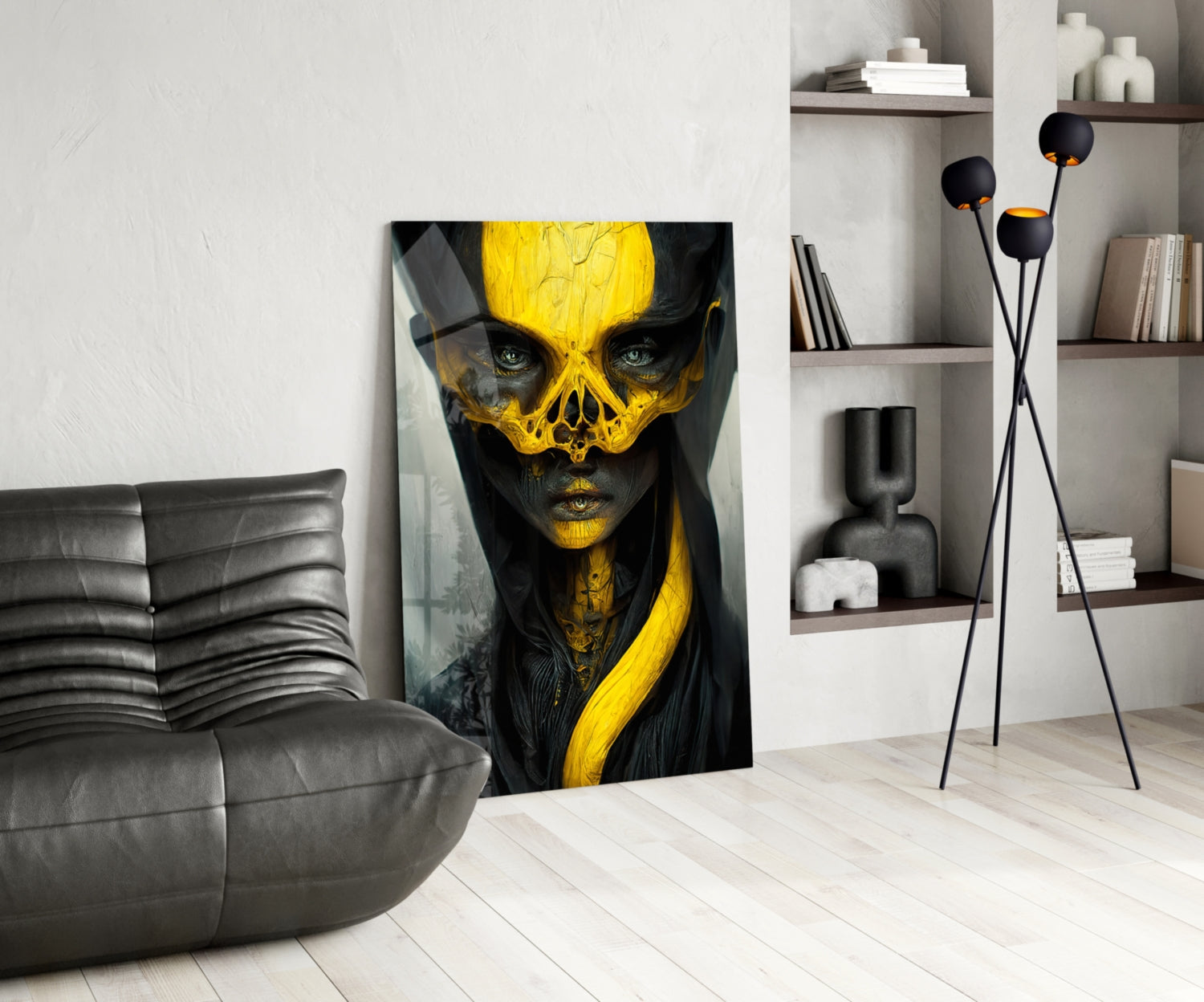 Yellow and black skull face portrait artwork displayed against white wall in modern living room with gray sofa and shelving.