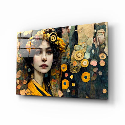 Glass wall art panel displayed at an angle showing ornate portrait of woman with gold headpiece and circular decorative elements in gold and teal tones.