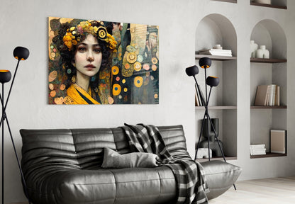 Glass wall art depicting a woman with dark hair and golden floral crown against ornate patterned background, displayed above black leather sofa in modern living room.