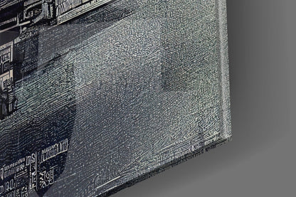 Close-up angled view of textured glass wall art showing detailed etched patterns and monochromatic grayscale surface with visible text along edges.