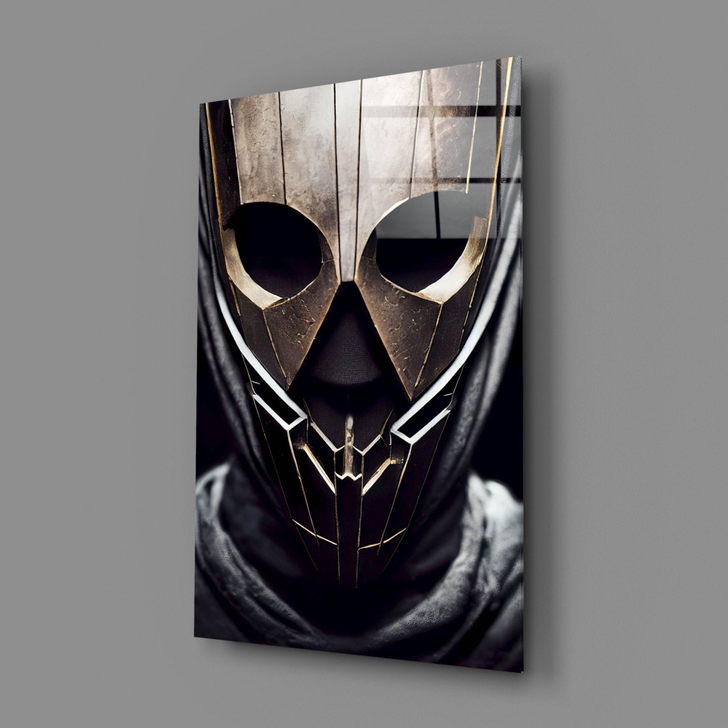 Angled view of glass art panel featuring metallic gold and black geometric mask design with circular eye cutouts against gray background.