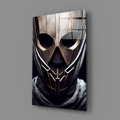 Angled view of glass art panel featuring metallic gold and black geometric mask design with circular eye cutouts against gray background.