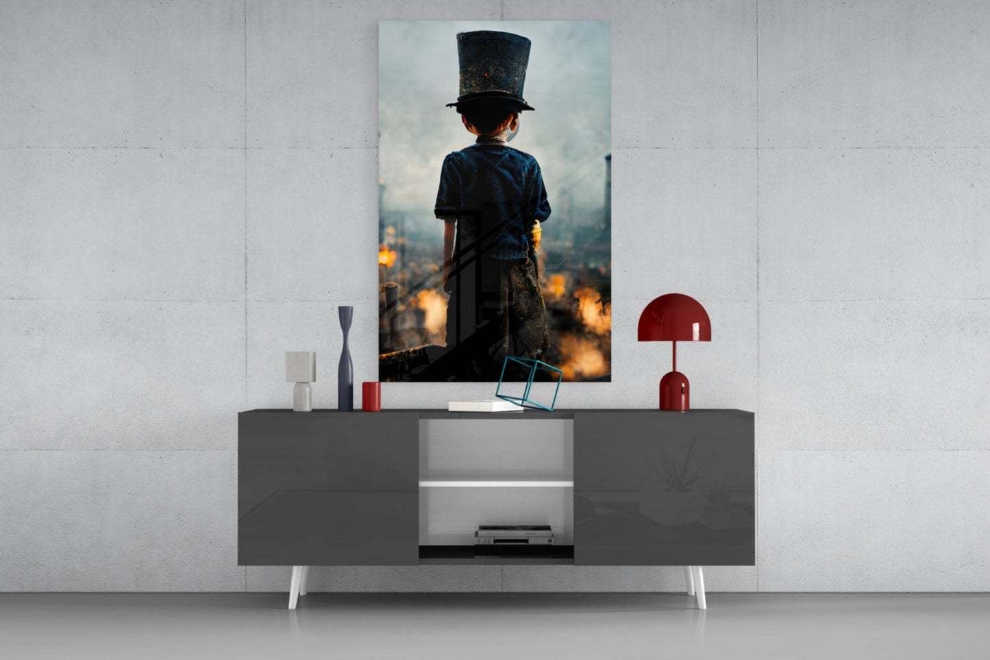 Vertical glass art print displayed on wall above gray console table, showing child in top hat overlooking burning cityscape at golden hour.