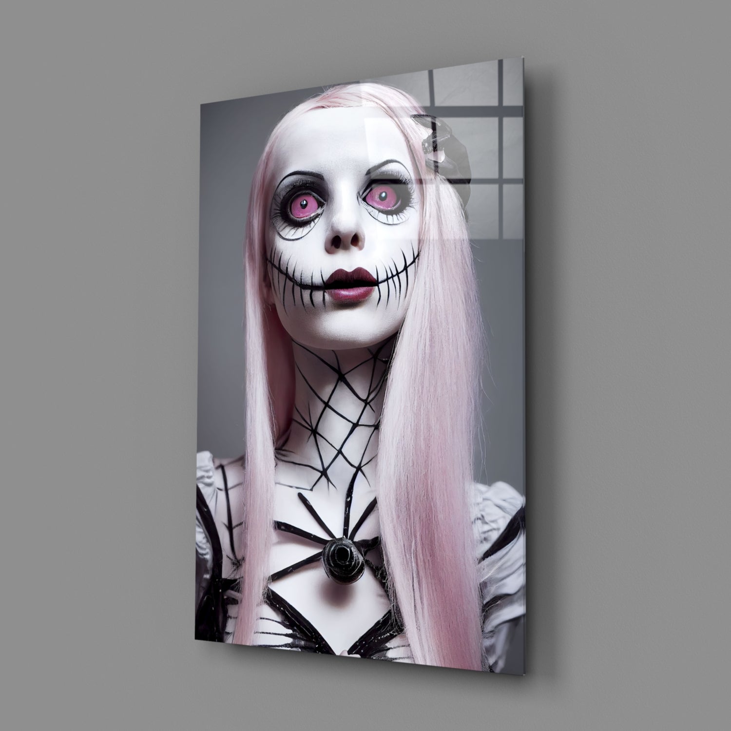 Glass wall art print mounted on gray wall showing pale-skinned figure with pink eyes, stitched mouth, long pink hair, and black geometric body markings.