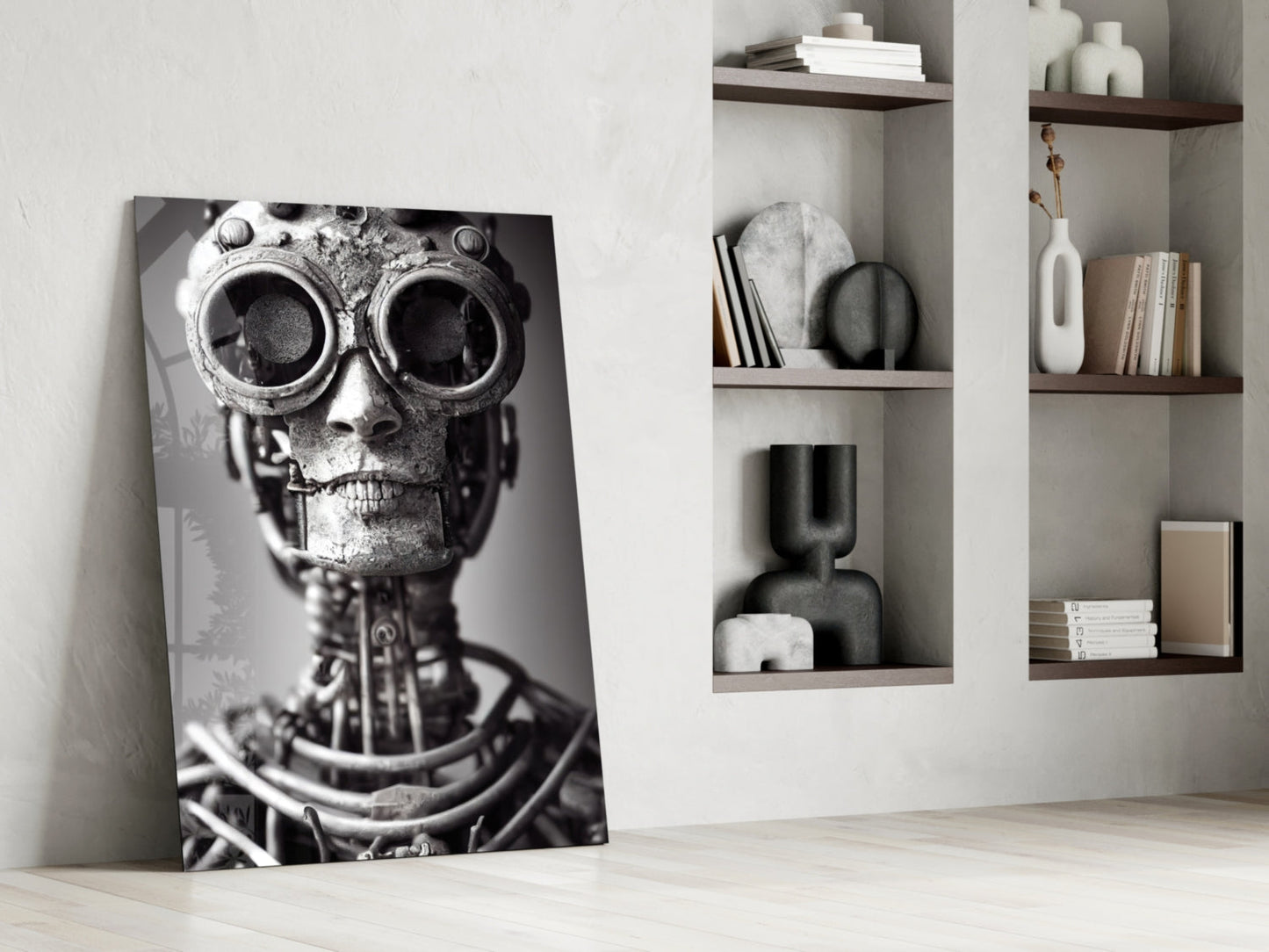 Black and white glass art panel leaning against white wall beside wooden shelving, depicting mechanical skull with large circular eyes and metallic details.